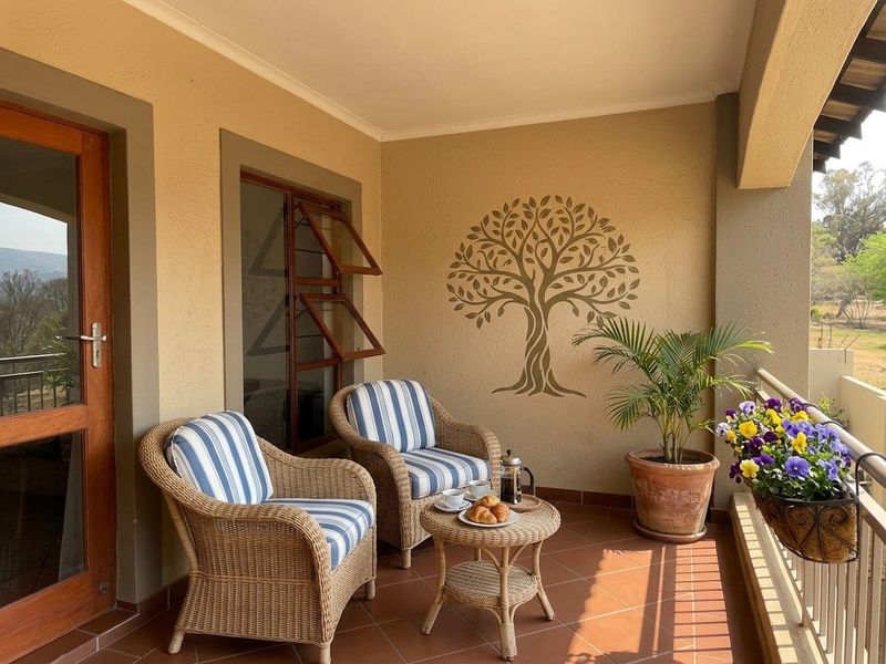 A covered balcony featuring tiled flooring, timber-framed doors, and a metal balustrade, offering a pleasant outdoor space with natural light.