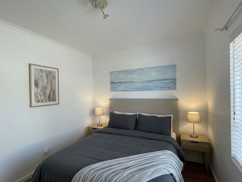A well-maintained bedroom featuring neutral walls, timber-look flooring, and venetian blinds, providing a clean and comfortable living space.