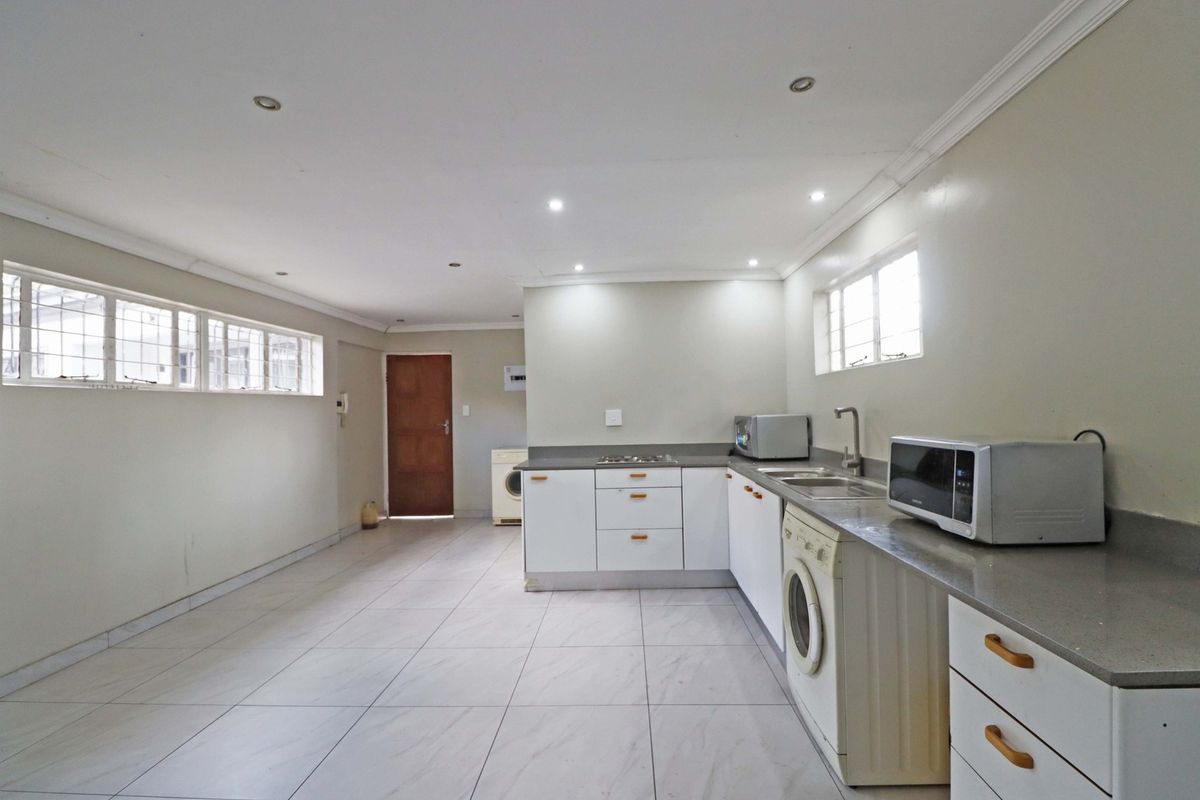 A functional kitchen area featuring built-in cabinetry, stone countertops, and tiled flooring, offering a clean and practical space for culinary activities.