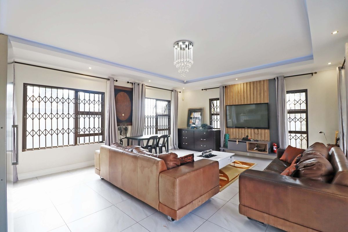 Spacious living room featuring tiled flooring, a timber slat feature wall, recessed ceiling lighting, and a decorative crystal chandelier.