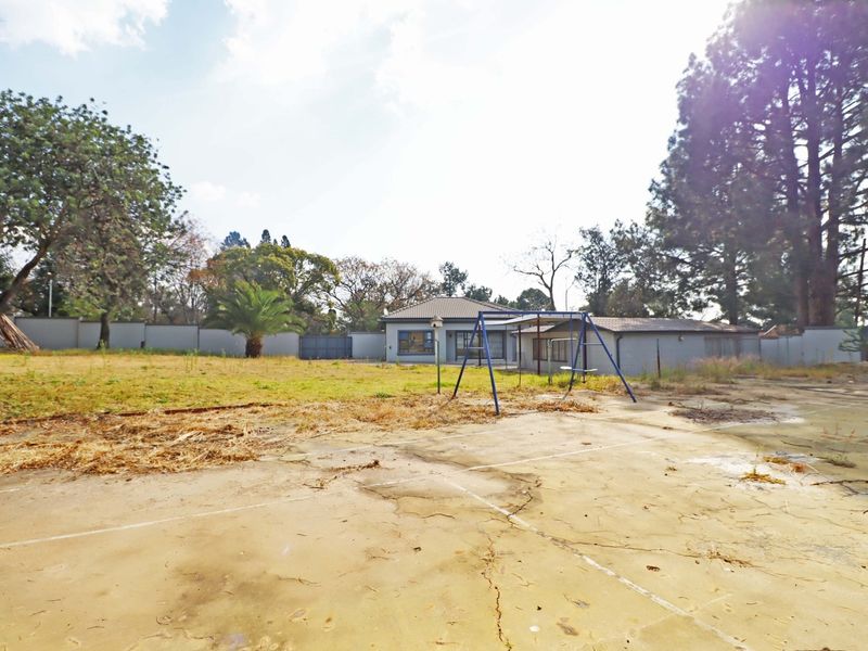 A spacious rear yard featuring a large concrete paved area, lawn, and perimeter walling, offering significant potential for landscaping and outdoor development.