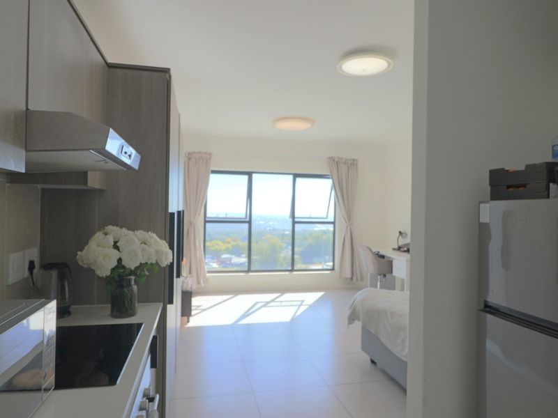 An open-plan apartment layout featuring a modern kitchen with built-in cabinetry and a bright living area with expansive windows offering scenic views.