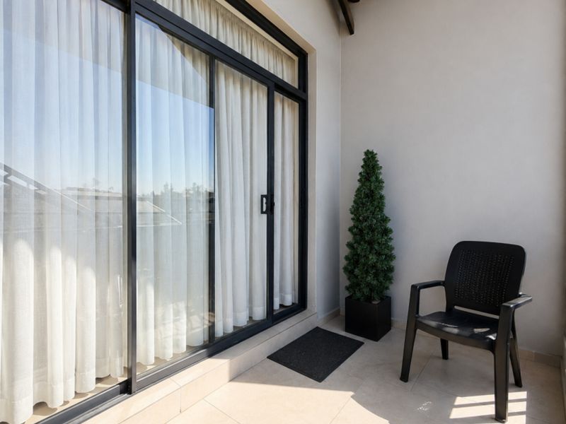 A clean, covered balcony featuring tiled flooring and large sliding glass doors providing access to the interior living space.