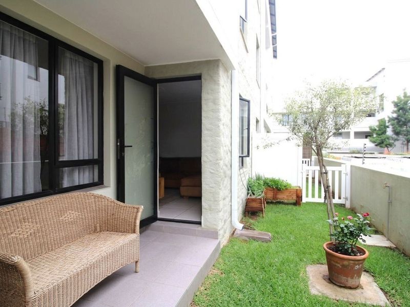 A private ground floor patio area featuring tiled flooring, direct access to the interior, and a small adjacent garden space with boundary walling.