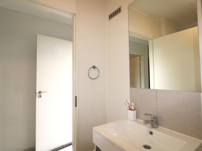 A clean and functional bathroom featuring a modern vanity basin, chrome fixtures, and a large wall-mounted mirror.