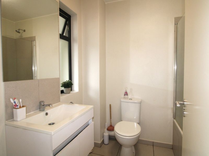 A clean and functional bathroom featuring a modern vanity with basin, a toilet, and a shower enclosure with a glass door.