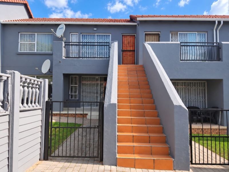 Front elevation of a multi-level apartment unit featuring a prominent tiled staircase, security gates, and balcony access with modern grey exterior paint.