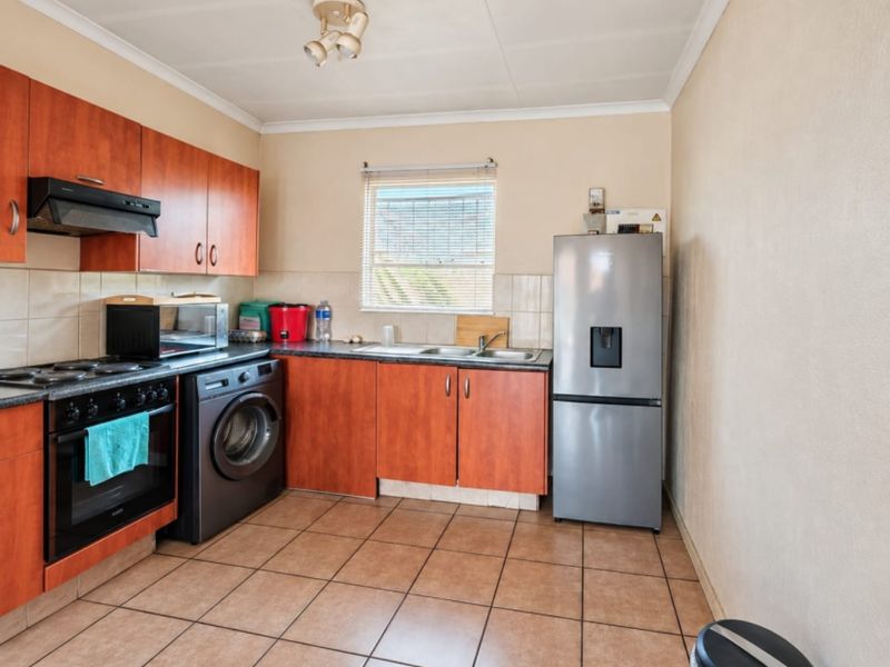 Functional kitchen featuring laminate cabinetry, built-in oven with extractor fan, double sink, and tiled flooring, offering a practical layout for daily use.
