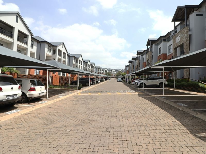 A well-maintained apartment complex driveway featuring paved surfaces and covered parking bays for residents.