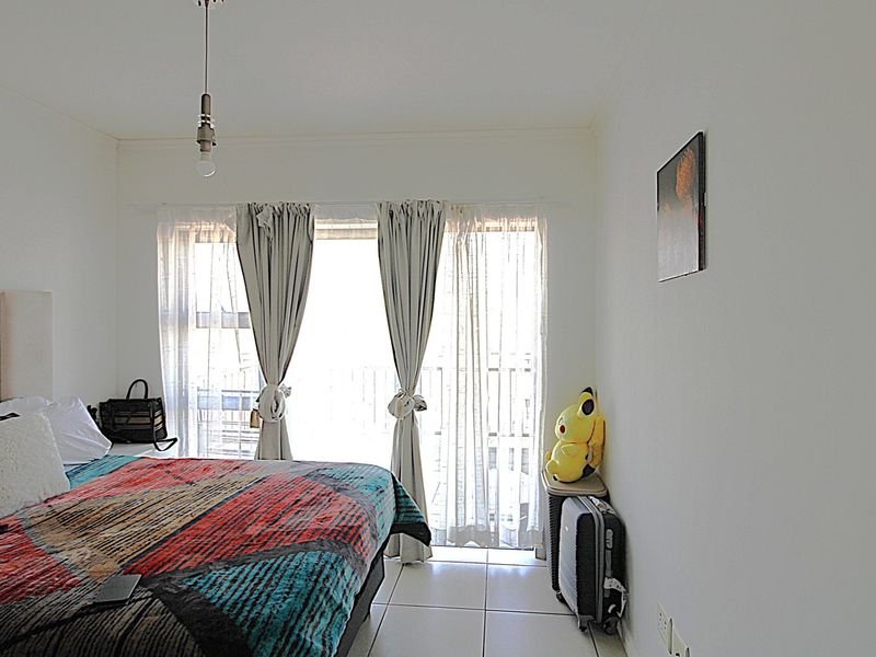 A bedroom featuring tiled flooring and a sliding glass door that provides access to an outdoor area, allowing for natural light.