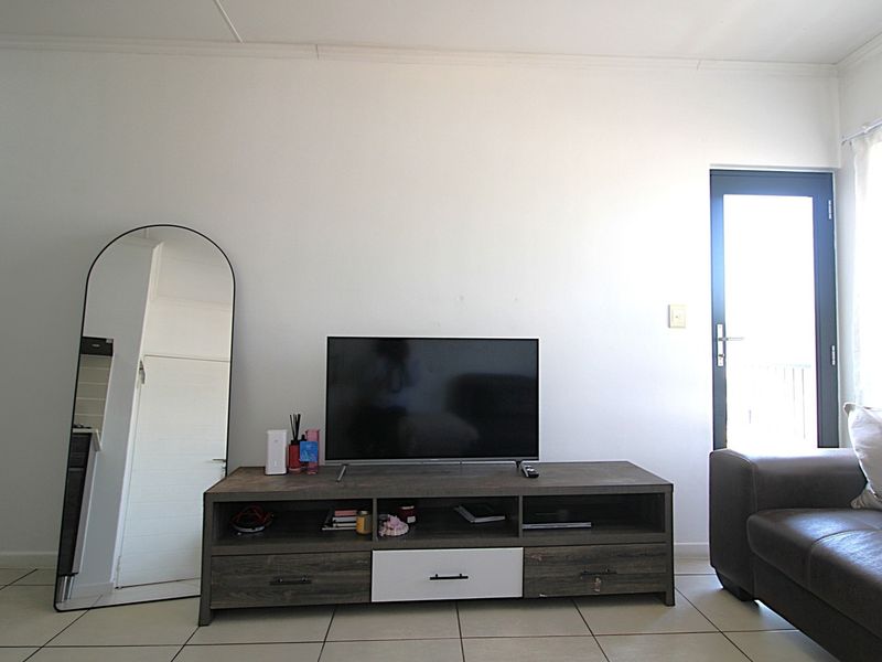 A living room area featuring tiled flooring and a glass panel door leading to an outdoor space.