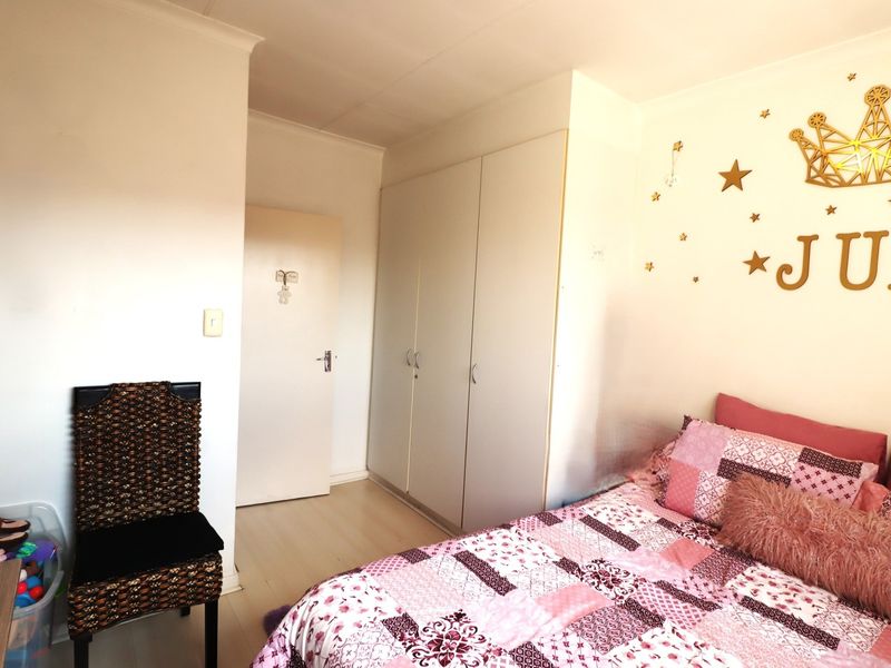 A well-maintained bedroom featuring neutral laminate flooring and practical built-in cupboards, offering a clean and functional living space.