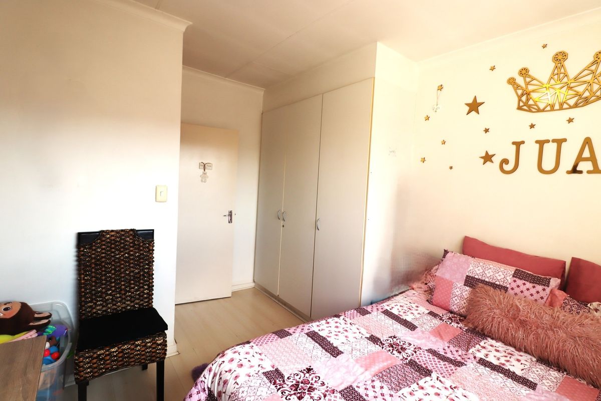A well-maintained bedroom featuring neutral laminate flooring and practical built-in cupboards, offering a clean and functional living space.