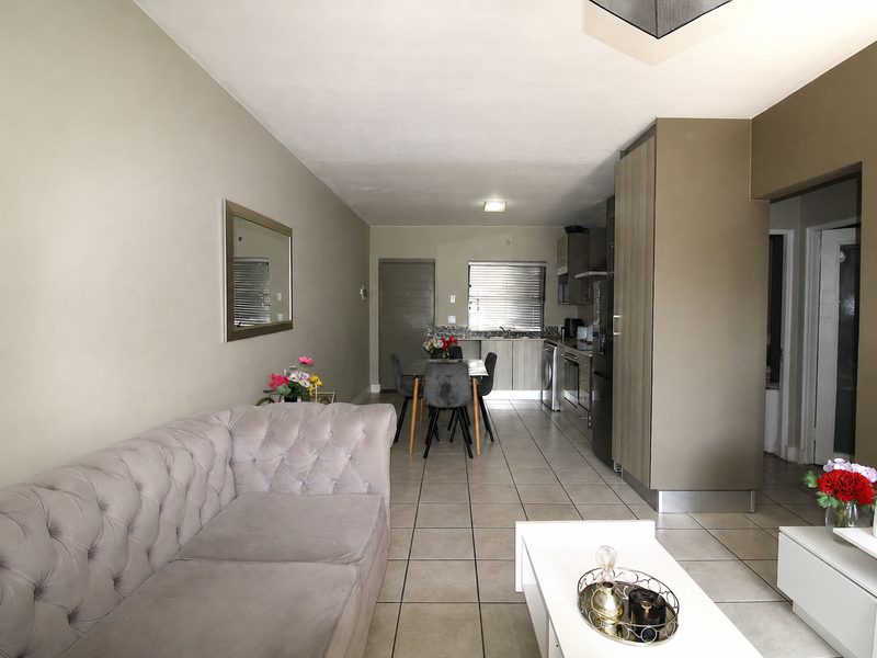 Open-plan living and kitchen area featuring tiled flooring and functional built-in cabinetry, providing a cohesive space for dining and relaxation.