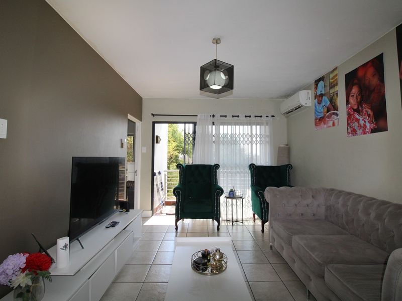 A living room featuring tiled flooring, an air conditioning unit, and a sliding glass door leading to an outdoor balcony area.
