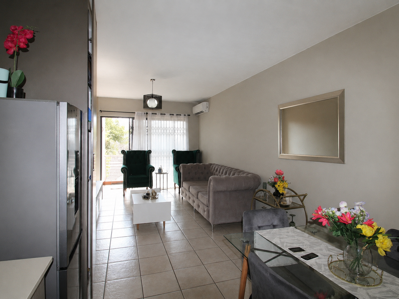An open-plan living and dining area featuring tiled flooring, a split-system air conditioner, and sliding glass doors leading to an outdoor space.