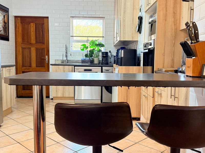 A functional kitchen featuring light wood-look cabinetry, a subway tile backsplash, built-in oven and microwave, and a convenient breakfast bar area.