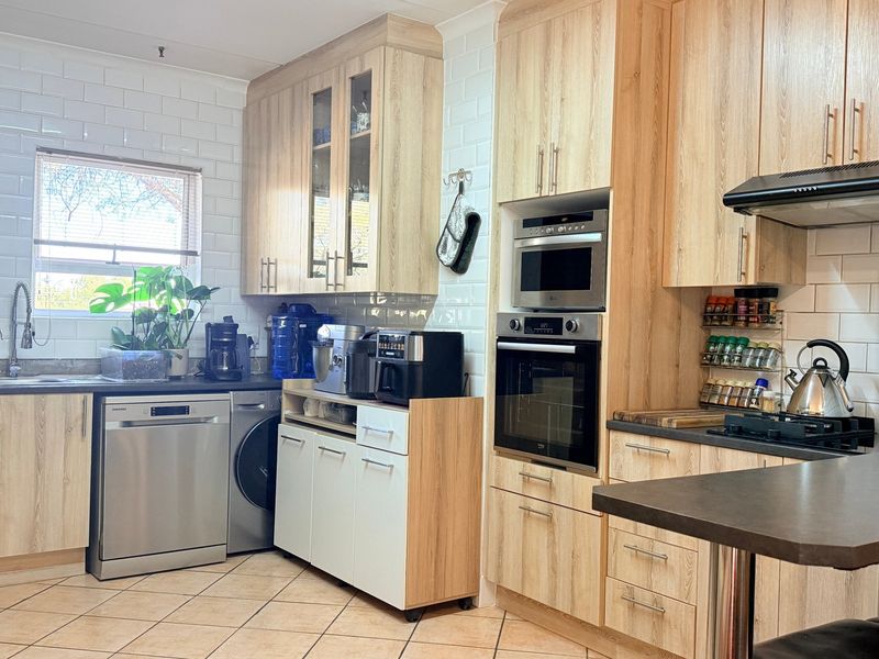 A well-maintained kitchen featuring light wood cabinetry, subway tile backsplash, built-in oven and microwave, and a functional layout with ample counter space.