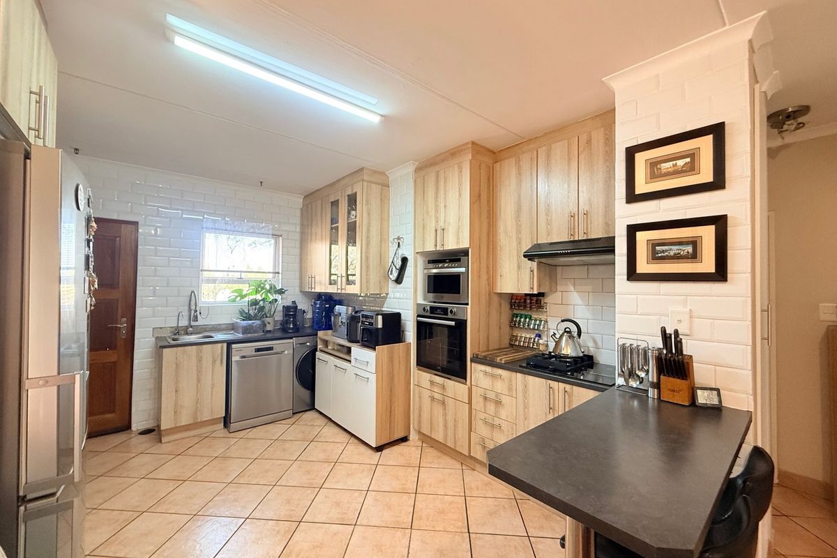 A well-maintained kitchen featuring light wood cabinetry, subway tile backsplash, built-in appliances, and a functional breakfast bar area.
