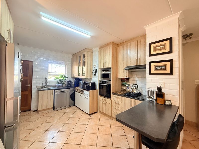 A well-maintained kitchen featuring light wood cabinetry, subway tile backsplash, built-in appliances, and a functional breakfast bar area.