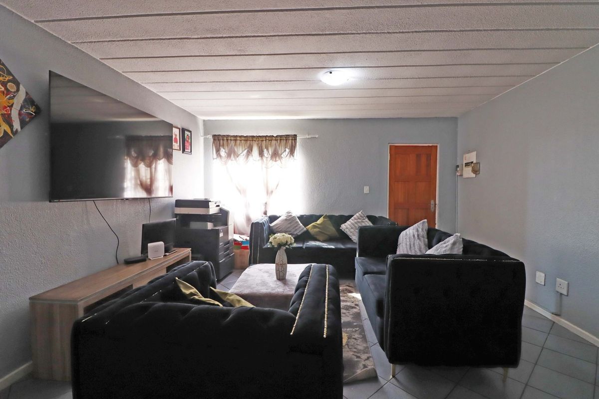 A living room featuring tiled flooring and a textured ceiling, providing a functional space for relaxation and entertainment.