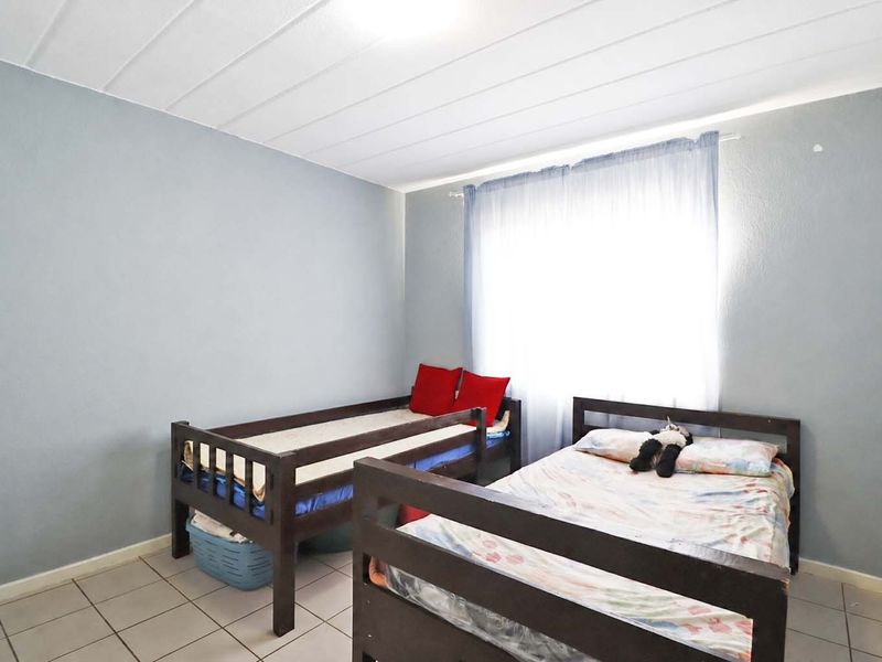 A functional bedroom featuring tiled flooring and a panelled ceiling, providing a neutral base for personalization.