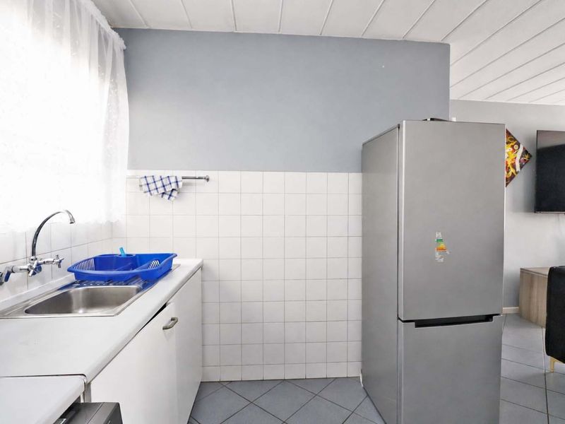 A functional kitchen area featuring a stainless steel sink, tiled backsplash, and built-in cabinetry, seamlessly flowing into the adjacent living space.