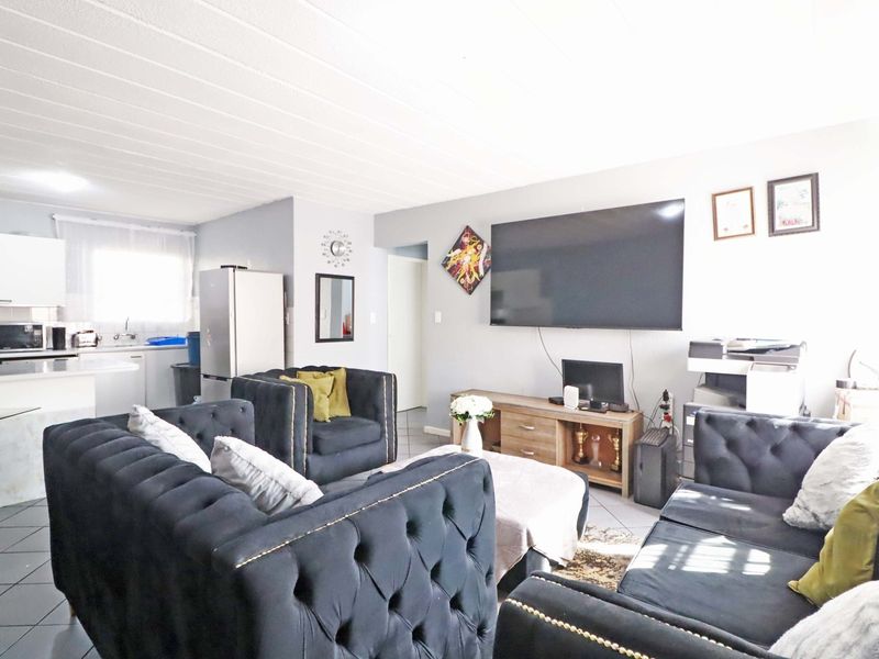 Open-plan living area featuring tiled flooring and an integrated kitchen space with cabinetry and countertops.