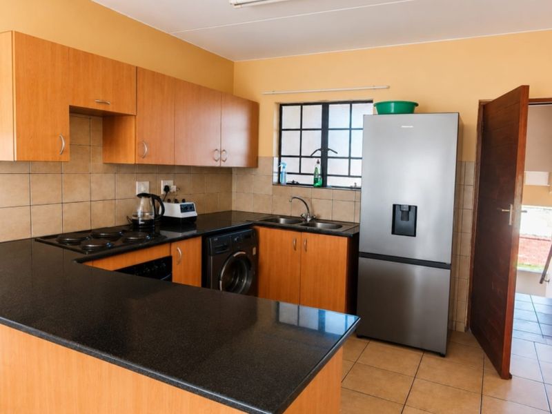 Functional kitchen featuring laminate cabinetry, granite countertops, a double basin sink, and built-in cooking appliances with tiled flooring and backsplash.