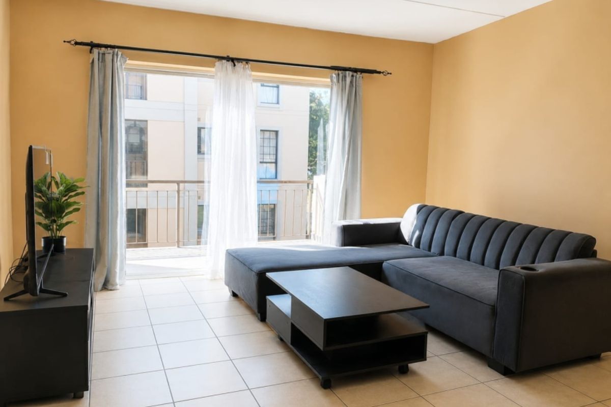 A living room featuring tiled flooring and a sliding glass door providing access to a balcony, with neutral wall tones.