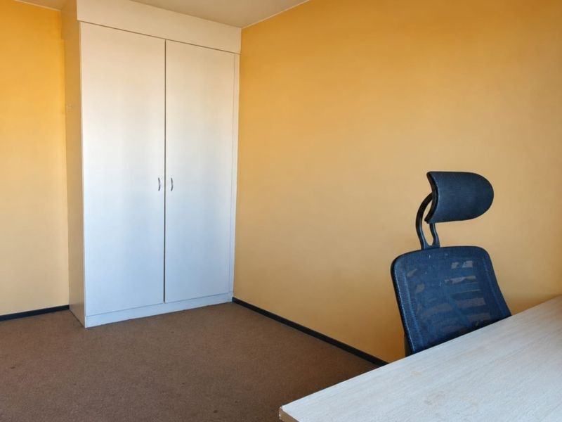 A simple bedroom featuring a built-in wardrobe and carpeted flooring, offering a functional space ready for personalization.
