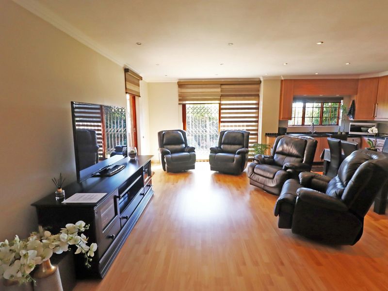 Open-plan living and kitchen area featuring laminate flooring, recessed lighting, and sliding glass doors leading to the exterior.