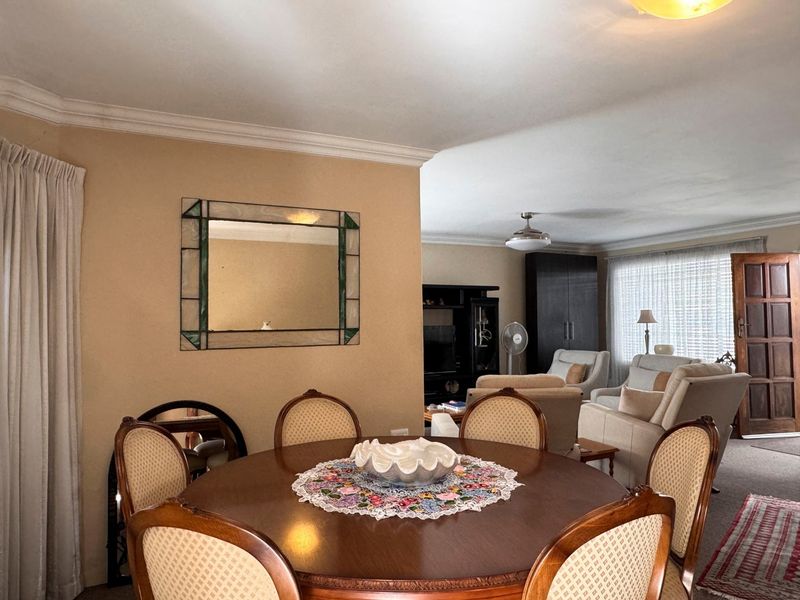 Open plan living and dining area featuring neutral wall tones, decorative ceiling cornicing, and access to a timber entrance door.