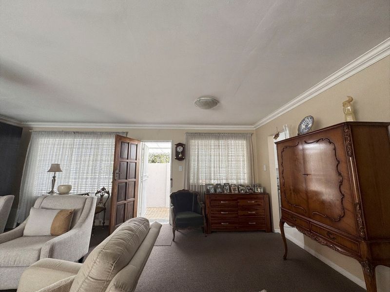 A spacious living room featuring crown molding, neutral wall finishes, and direct access to an outdoor area through a timber panel door.