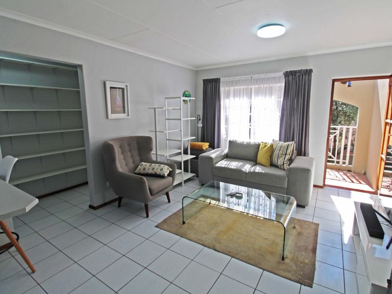 A bright living room featuring tiled flooring, built-in shelving, and direct access to an outdoor balcony area.
