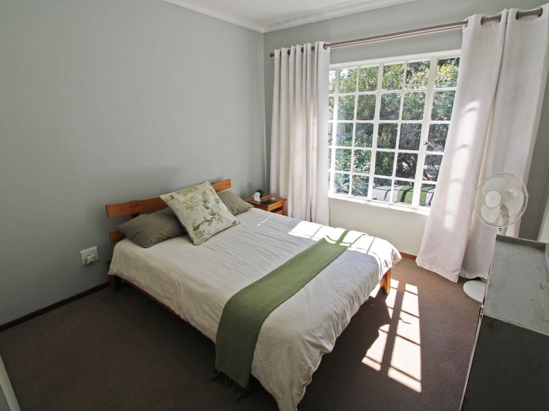 A well-lit bedroom featuring carpeted flooring and a large multi-pane window that allows for ample natural light.