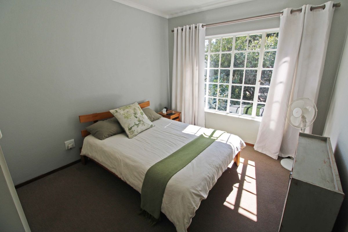 A well-lit bedroom featuring carpeted flooring and a large multi-pane window that allows for ample natural light.