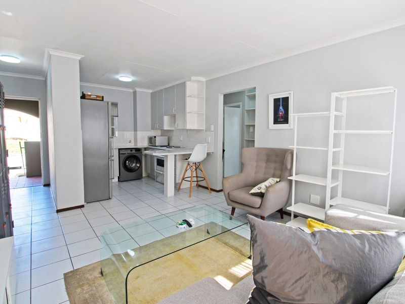 An open-plan living area featuring a functional kitchen with built-in cabinetry, a breakfast counter, and tiled flooring throughout.