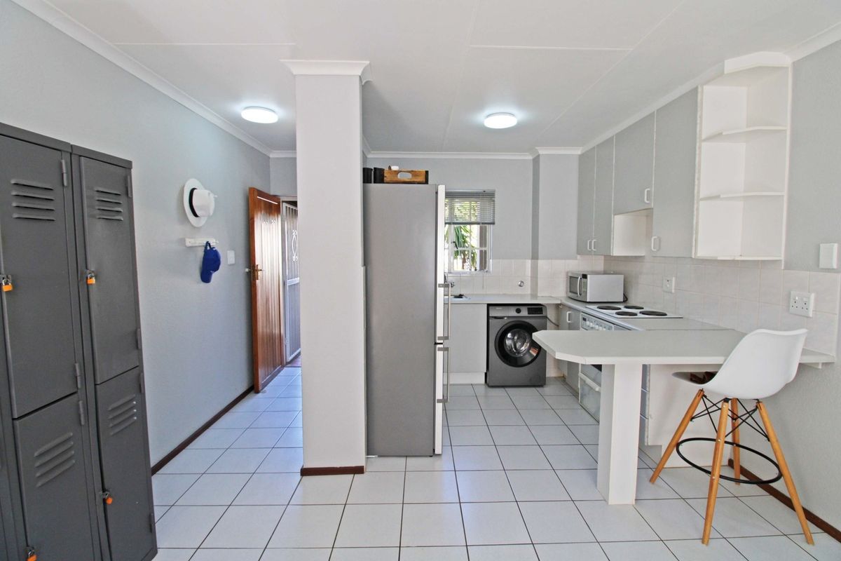 A functional kitchen featuring tiled flooring, built-in cabinetry, an electric hob, and an integrated breakfast bar area.