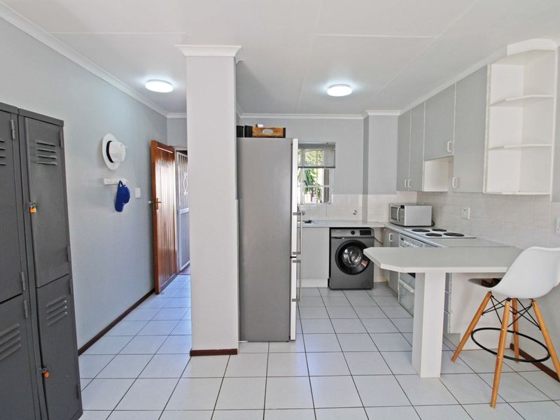 A functional kitchen featuring tiled flooring, built-in cabinetry, an electric hob, and an integrated breakfast bar area.