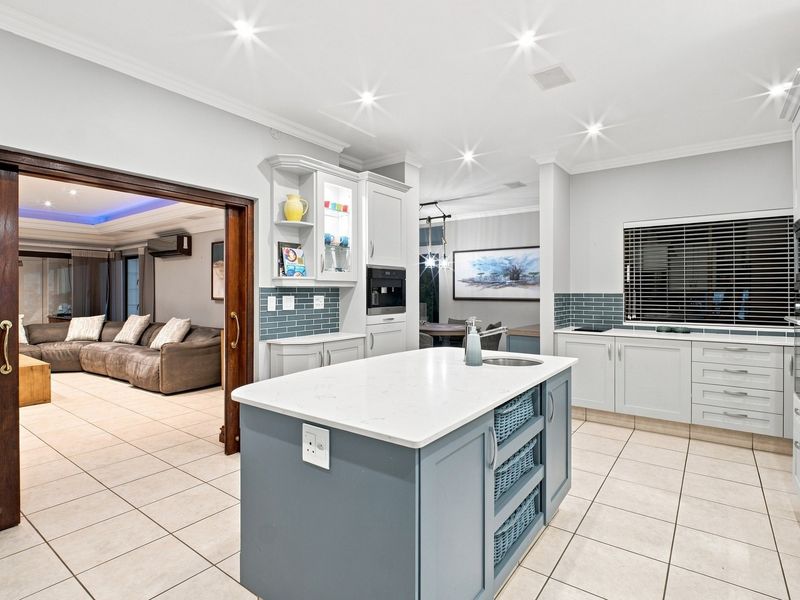 Modern kitchen featuring a central island with quartz countertops, built-in appliances, subway tile backsplash, and recessed lighting, seamlessly connecting to the adjacent living area.