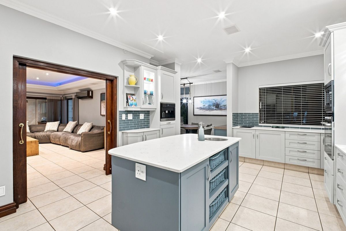 Modern kitchen featuring a central island with quartz countertops, built-in appliances, subway tile backsplash, and recessed lighting, seamlessly connecting to the adjacent living area.