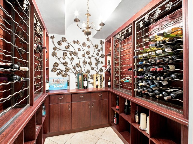 A well-appointed custom wine cellar featuring extensive built-in wooden wine racking, cabinetry, and decorative metal wall accents.