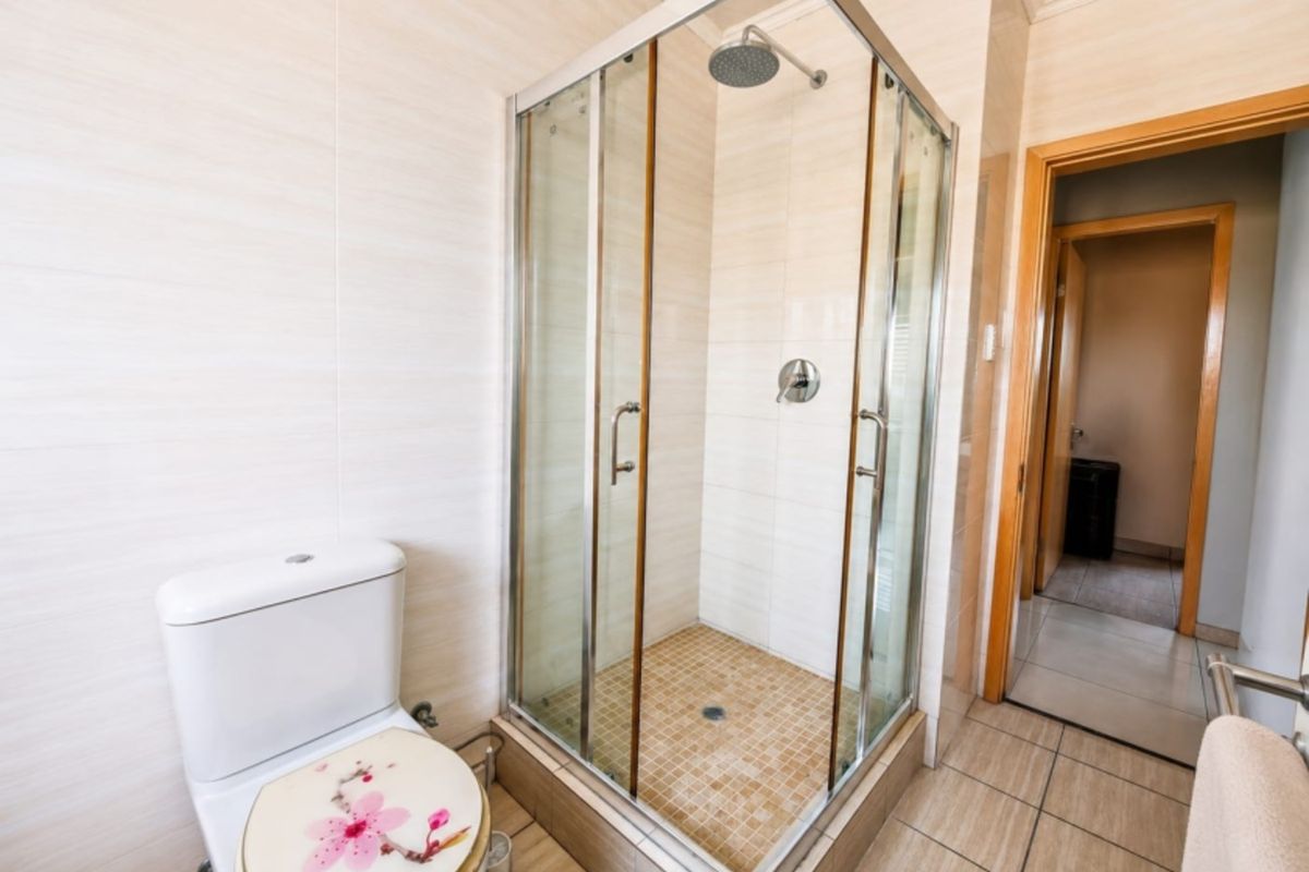 A clean, functional bathroom featuring a glass-enclosed shower, tiled walls, and standard toilet fixtures with neutral finishes.