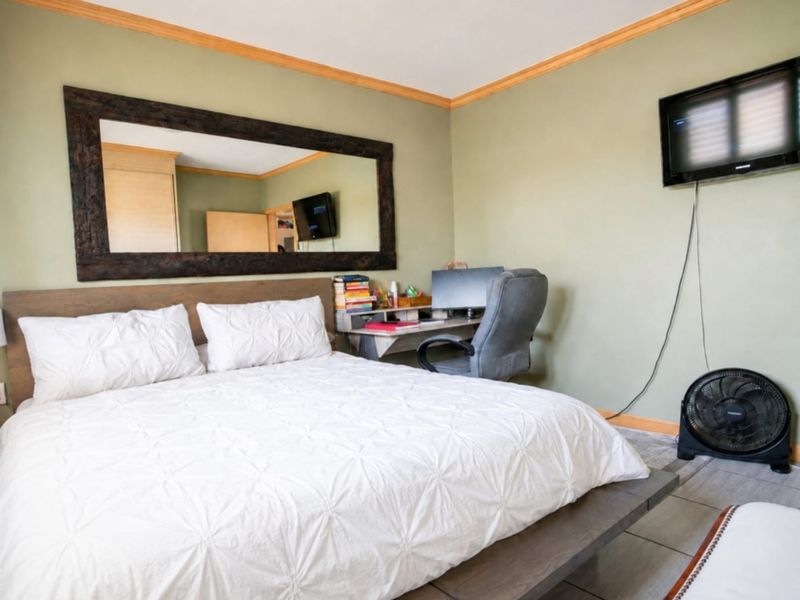 A bedroom featuring tiled flooring, crown molding, and a wall-mounted television. The space offers a functional layout with neutral wall tones.