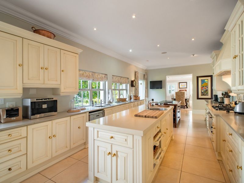 Spacious, well-appointed kitchen featuring a large central island, stone countertops, ample built-in cabinetry, and high-quality integrated appliances with recessed lighting.