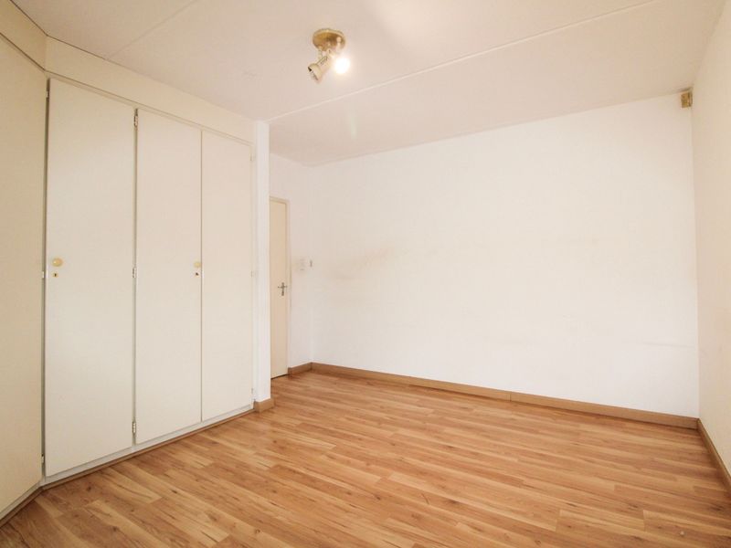 An empty bedroom featuring laminate flooring and built-in cupboards, providing a blank canvas for personalization.