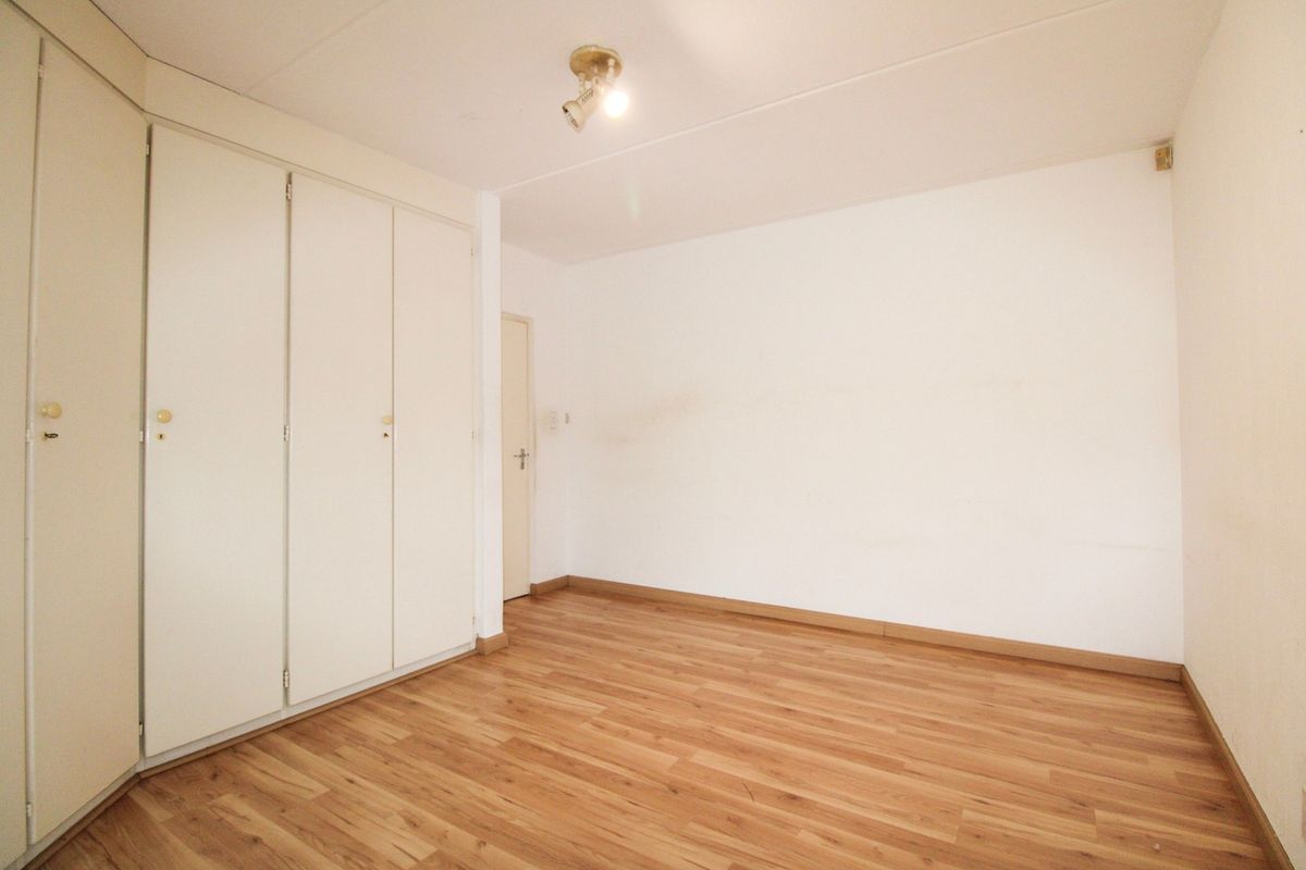 An empty bedroom featuring laminate flooring and built-in cupboards, providing a blank canvas for personalization.