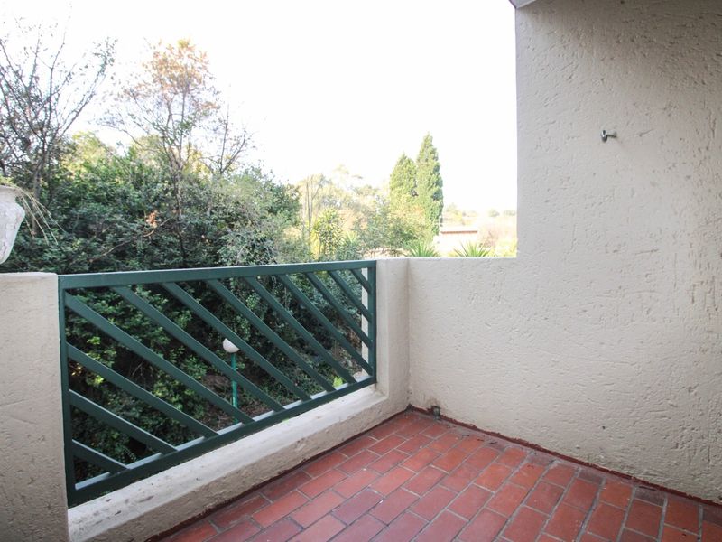 A private balcony featuring terracotta tile flooring, a metal balustrade, and views of the surrounding greenery.