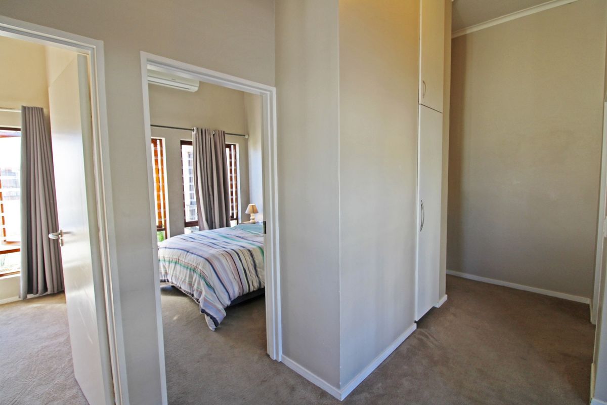 A bedroom featuring built-in cupboards, carpeted flooring, and an integrated air conditioning unit, with a view into an adjoining room.